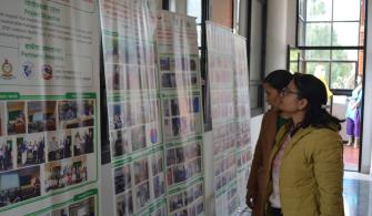 Meeting attendees looking at banners with information about the "Support for Healthcare Waste Management in Kathmandu 2021-2023" project.