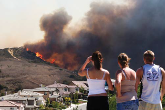 Residents survey wildfires sweeping through their community